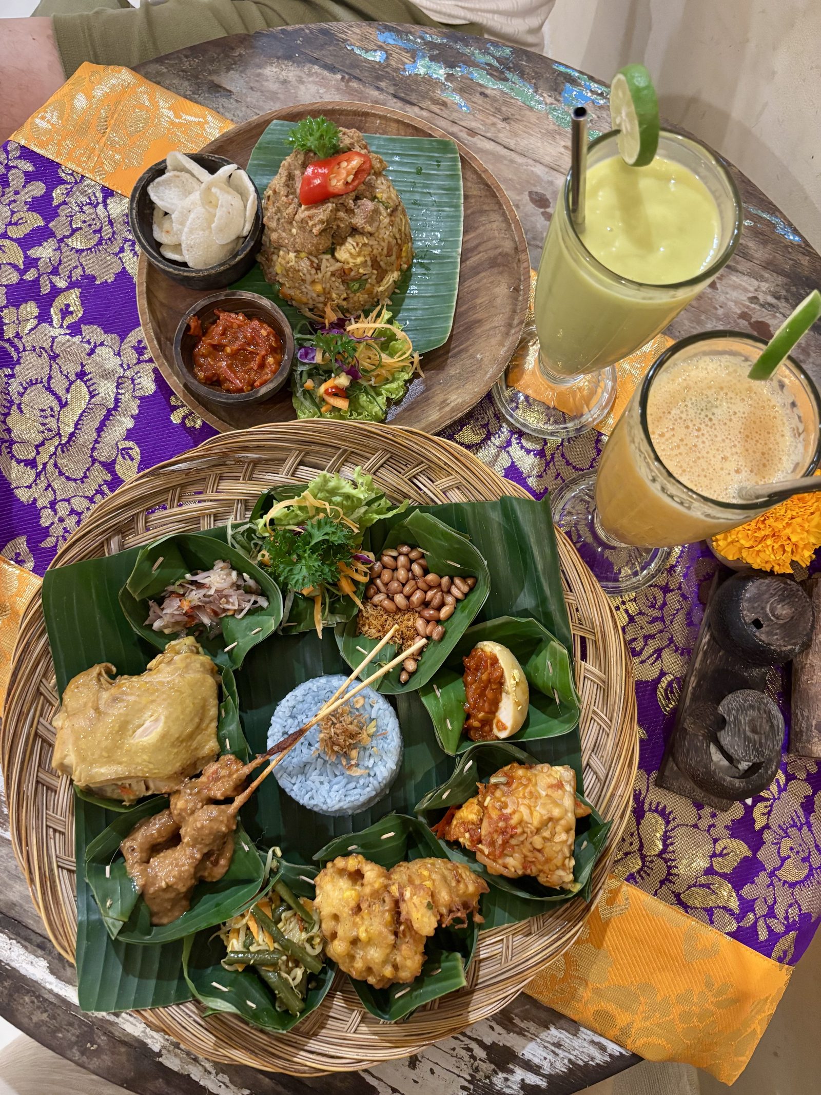 Nasi Campur balinés en cestillo de bambú con arroz azul y Nasi Goreng, con zumos tropicales