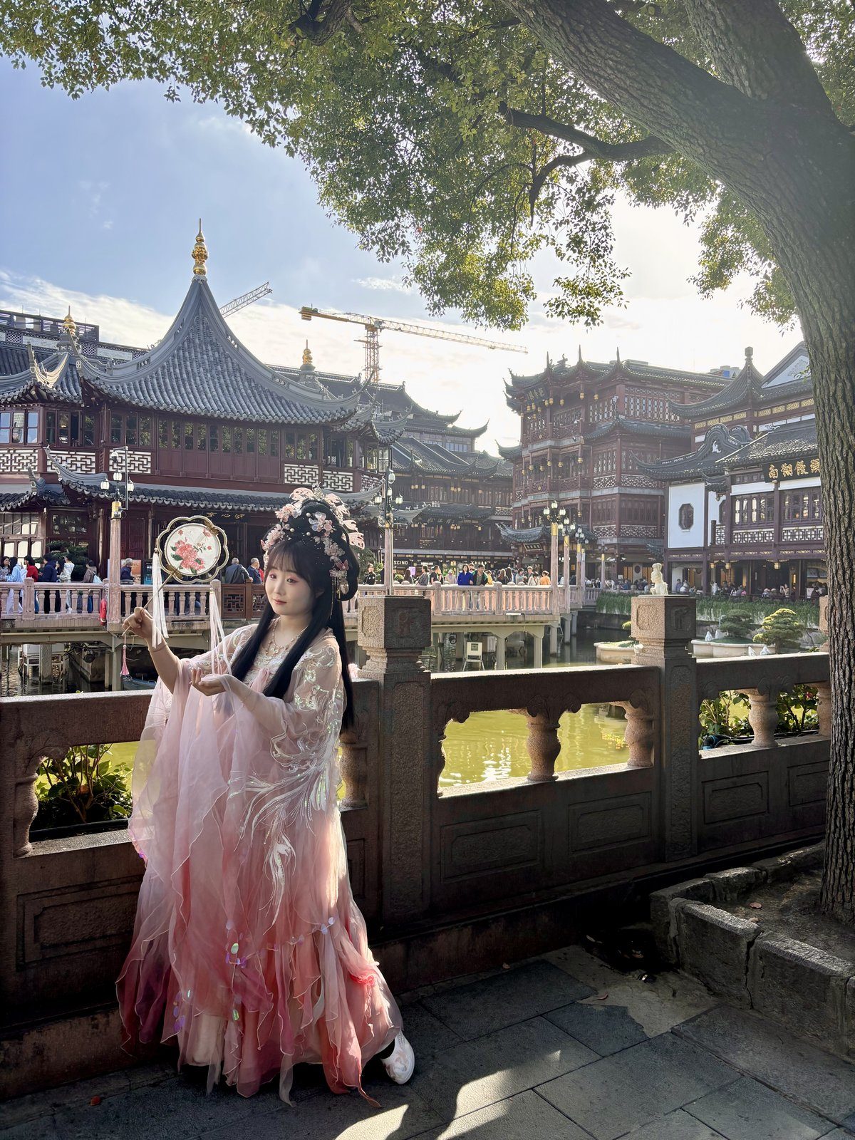 Chica joven vestida con hanfu rosa tradicional chino posando en el Jardín Yu con la arquitectura tradicional al fondo
