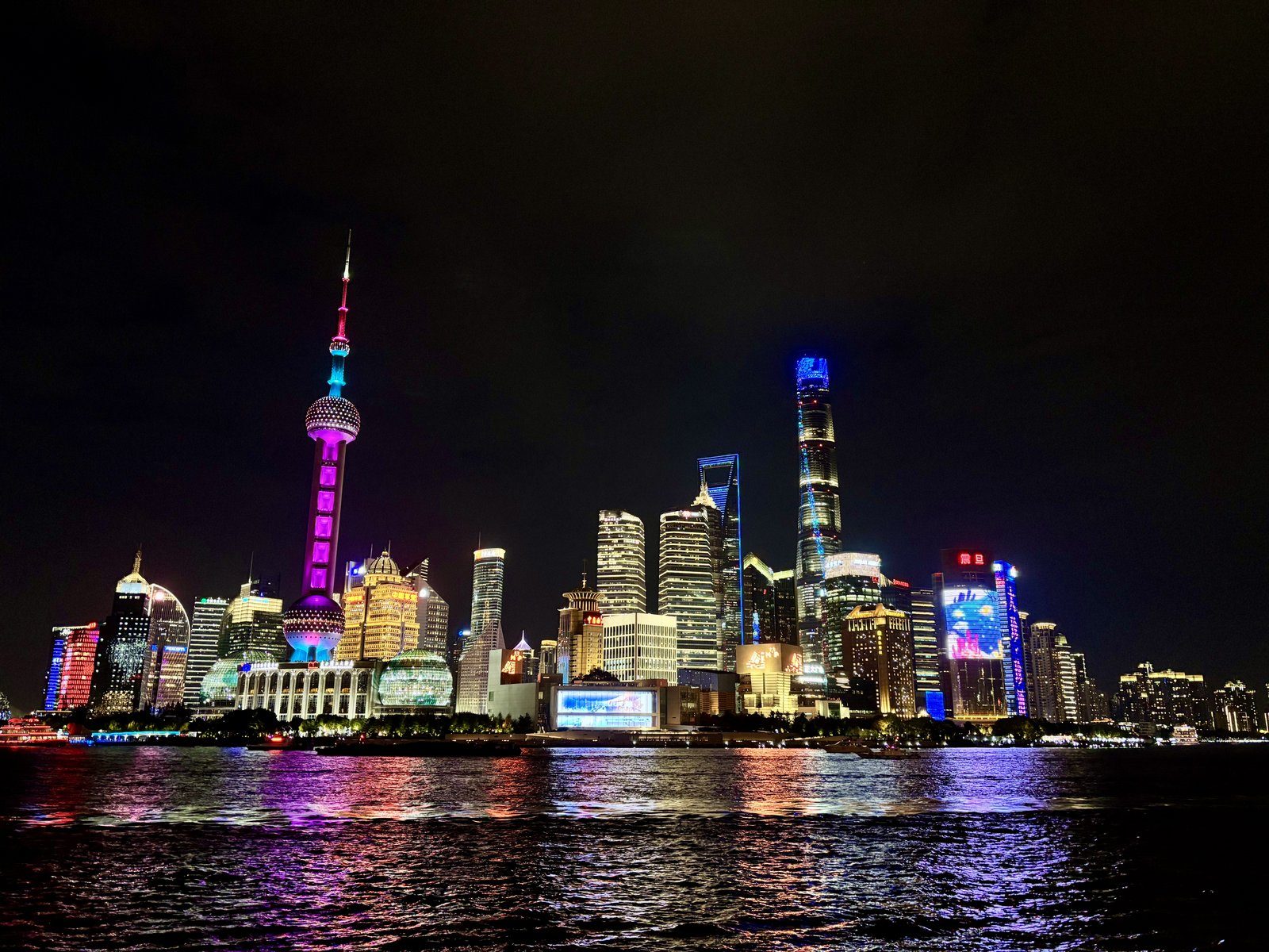 Skyline nocturno de Pudong desde el Bund con la Torre de la Perla Oriental iluminada en colores