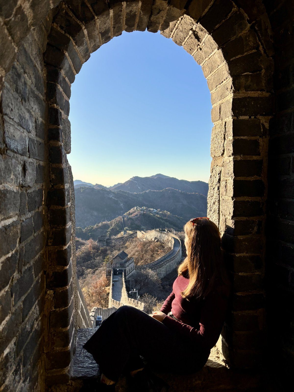 Vista de la Gran Muralla China a través de un arco de piedra de la torre de vigilancia con las montañas al fondo