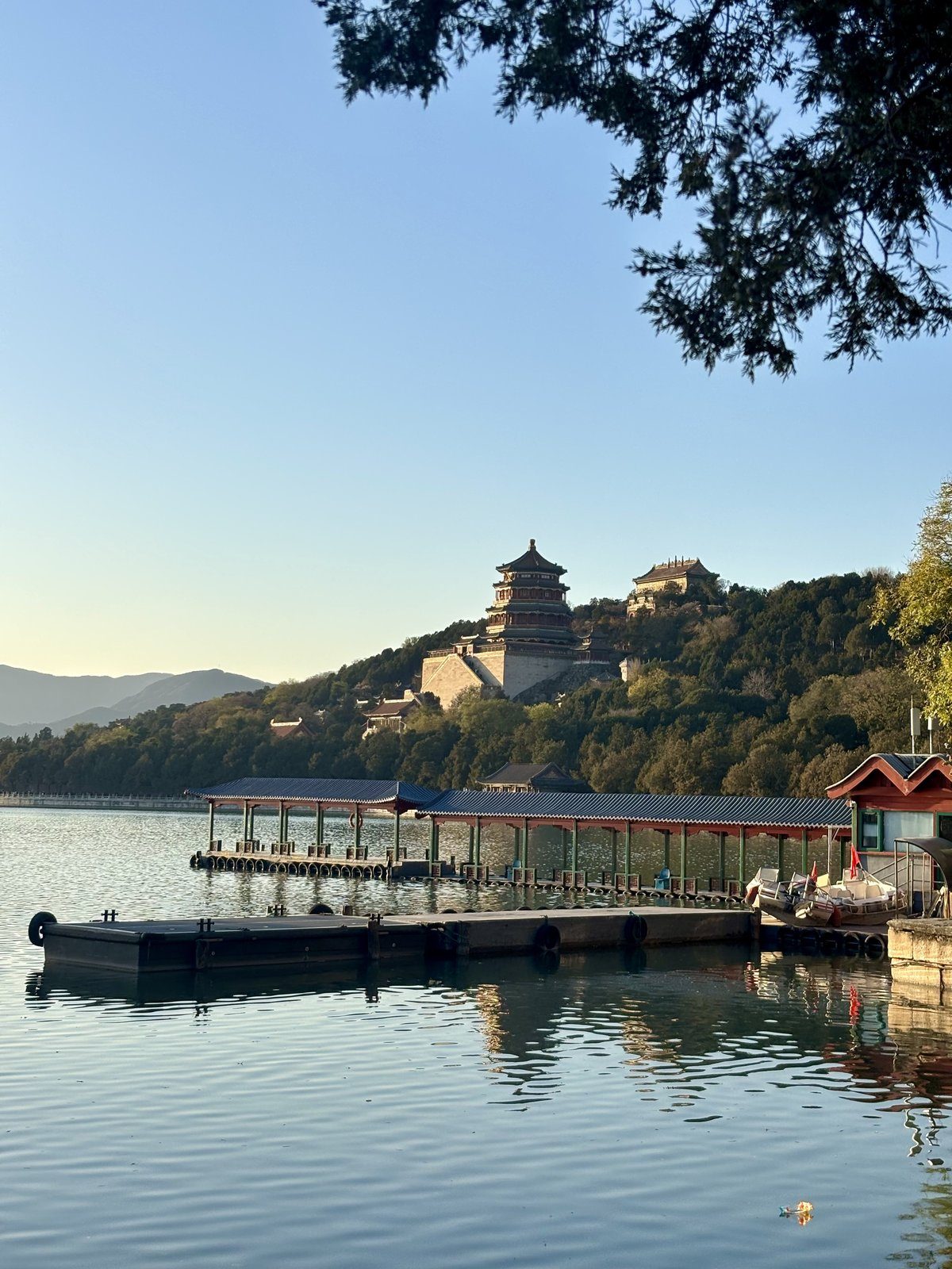 Palacio de Verano de Pekín con el lago Kunming en primer plano y el Pabellón de la Fragancia del Buda en la colina al fondo al atardecer