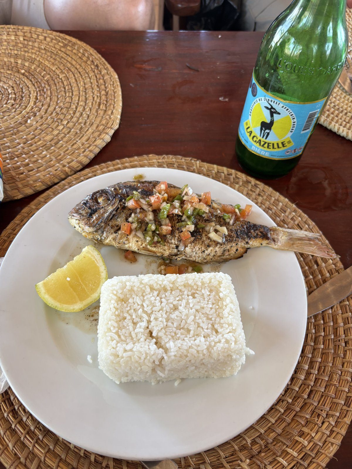 Pescado a la brasa con arroz y cerveza La Gazelle en restaurante local de Senegal