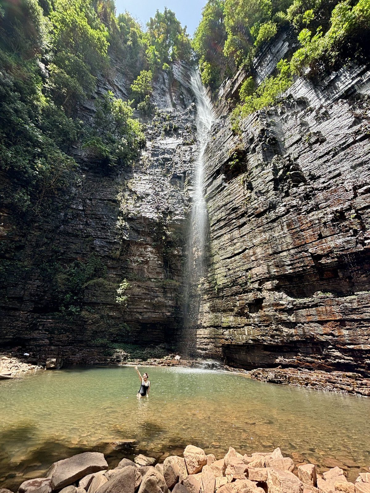 Cascada de Dindefelo de 115 metros con bañista en la poza, País Bassari, Senegal